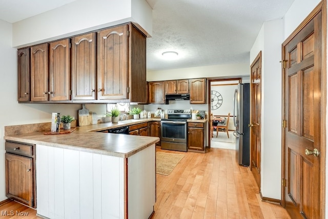 kitchen with light wood finished floors, stainless steel appliances, light countertops, a peninsula, and under cabinet range hood