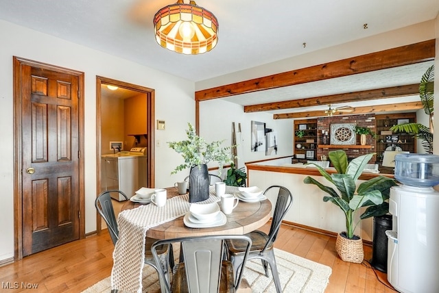 dining area with independent washer and dryer, light wood-style flooring, and beamed ceiling