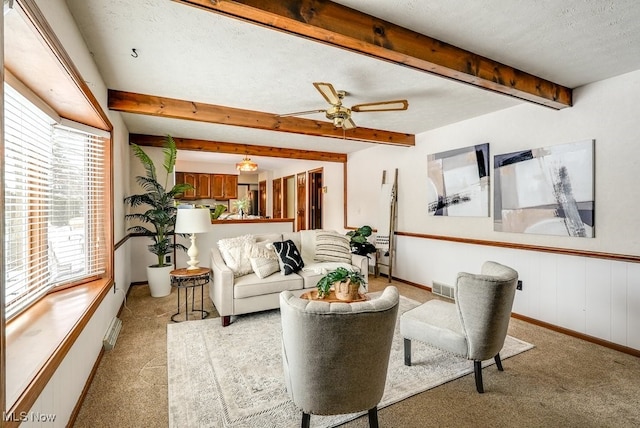 living room featuring a textured ceiling, light carpet, visible vents, a ceiling fan, and beamed ceiling