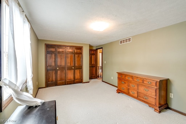 bedroom featuring baseboards, a closet, visible vents, and light colored carpet