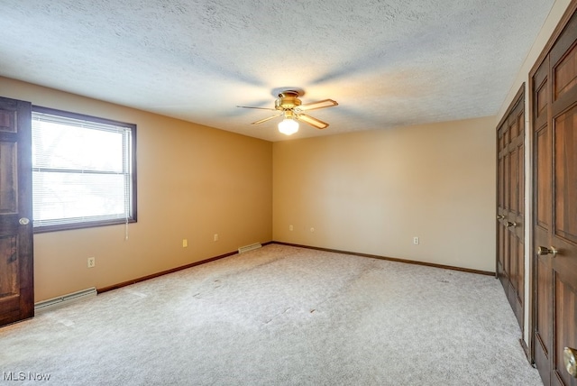 unfurnished bedroom featuring light colored carpet, visible vents, baseboards, and a textured ceiling