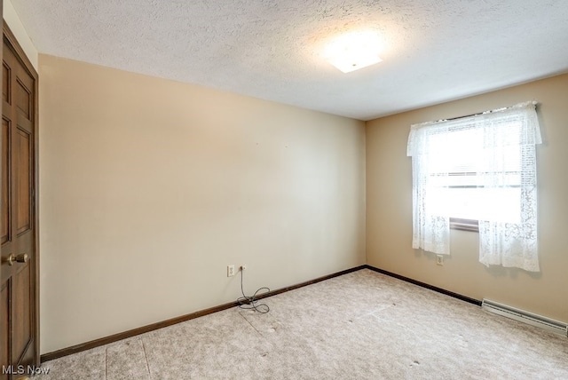 empty room featuring a textured ceiling, baseboard heating, light carpet, and baseboards