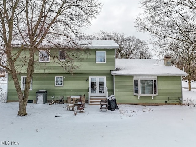 snow covered house featuring entry steps and a chimney