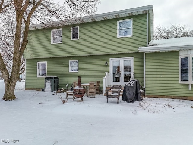 snow covered property with an outdoor fire pit and french doors