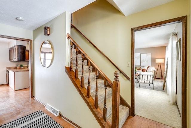 stairs featuring baseboards, visible vents, and wood finished floors