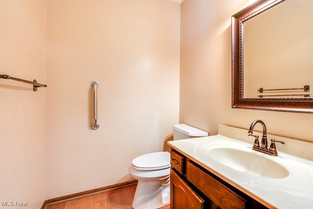 bathroom featuring baseboards, vanity, toilet, and wood finished floors