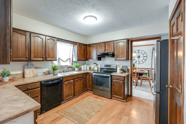 kitchen featuring appliances with stainless steel finishes, light wood-type flooring, light countertops, and under cabinet range hood