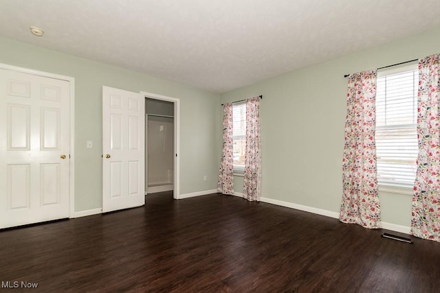 unfurnished bedroom featuring dark wood-style flooring, visible vents, and baseboards