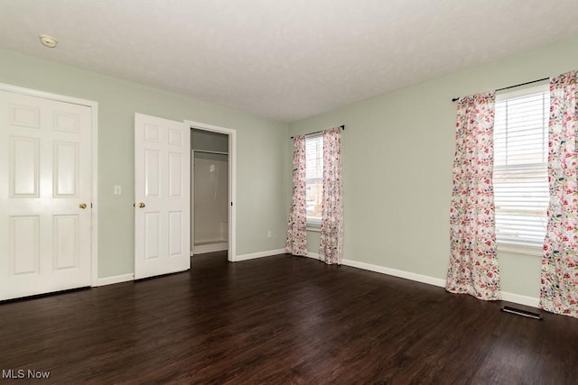 unfurnished bedroom featuring baseboards, wood finished floors, and visible vents