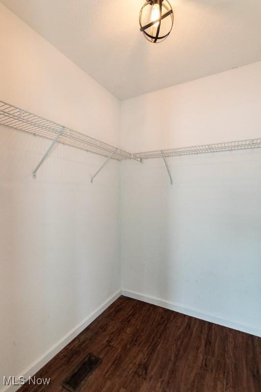 walk in closet with dark wood-style flooring and visible vents