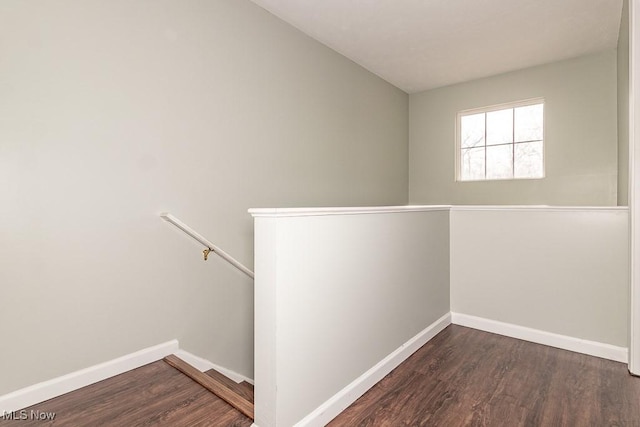 hallway featuring baseboards, dark wood-style flooring, and an upstairs landing