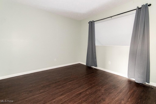 unfurnished room with wood finished floors, visible vents, and baseboards