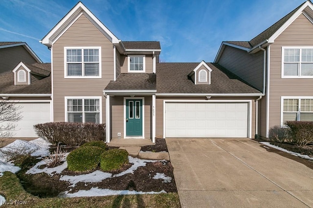 traditional-style home with an attached garage, a shingled roof, and driveway