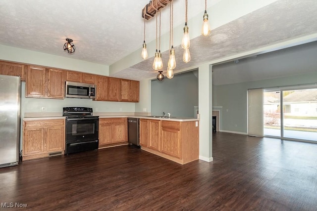 kitchen featuring pendant lighting, light countertops, appliances with stainless steel finishes, brown cabinetry, and a sink