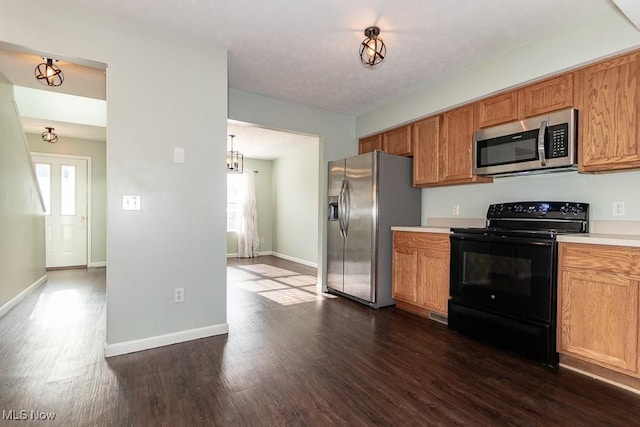 kitchen with brown cabinets, appliances with stainless steel finishes, light countertops, and dark wood-type flooring