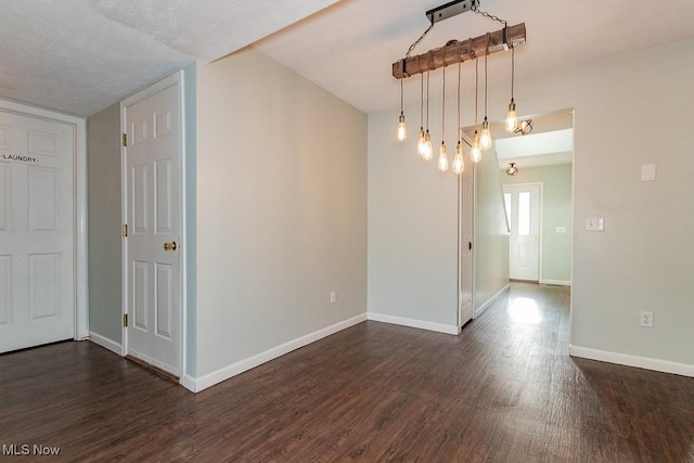 empty room featuring dark wood-type flooring and baseboards