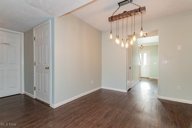 spare room featuring baseboards and dark wood-style floors
