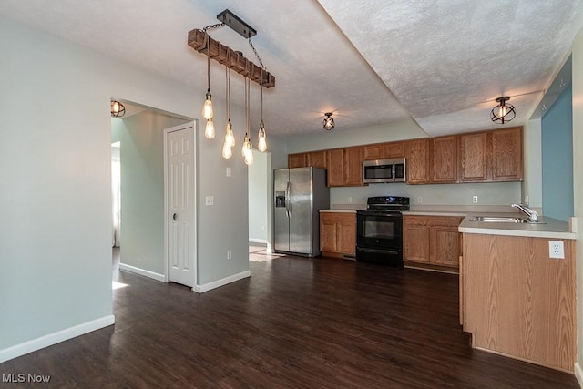 kitchen with a sink, light countertops, appliances with stainless steel finishes, brown cabinets, and pendant lighting