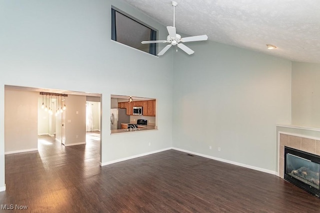 unfurnished living room featuring ceiling fan, dark wood-style flooring, a textured ceiling, a tiled fireplace, and high vaulted ceiling