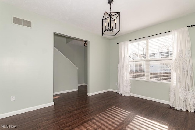 empty room featuring dark wood-style floors, baseboards, visible vents, and a notable chandelier