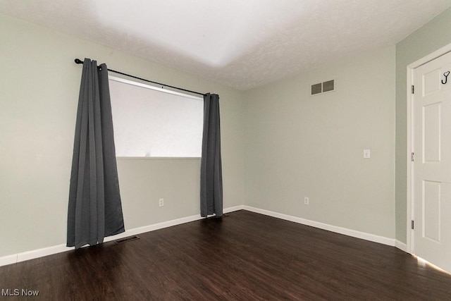 spare room featuring visible vents, baseboards, and wood finished floors