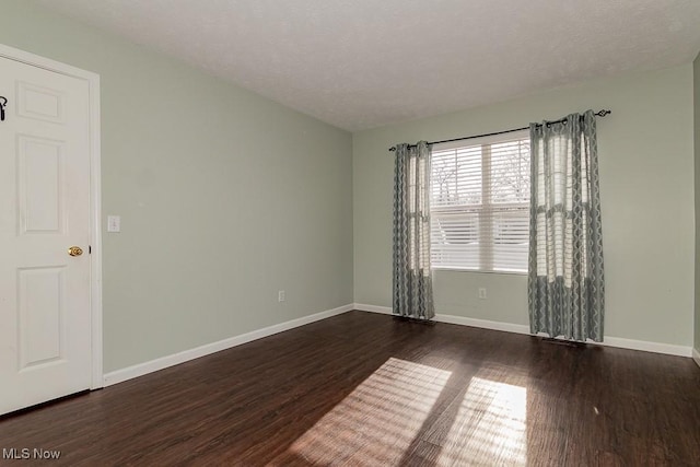 unfurnished room with dark wood-style floors and baseboards