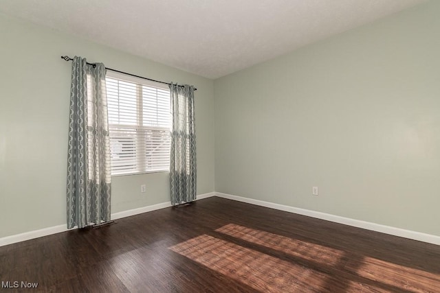 empty room with baseboards and wood finished floors