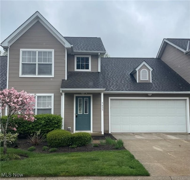 traditional-style home with an attached garage, a shingled roof, and driveway