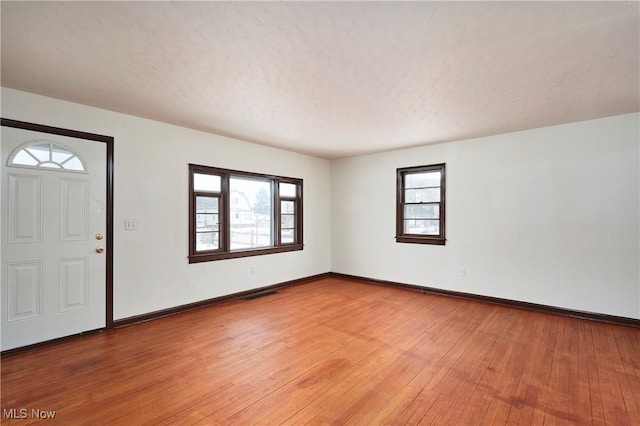 foyer entrance featuring visible vents, light wood-style flooring, baseboards, and a textured ceiling