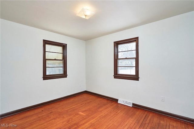 spare room featuring baseboards, visible vents, and wood finished floors