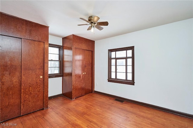 unfurnished bedroom featuring baseboards, visible vents, light wood finished floors, and multiple windows