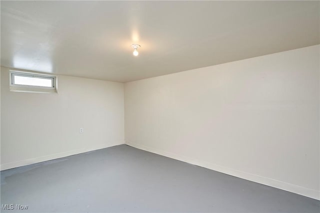 empty room with finished concrete floors and baseboards