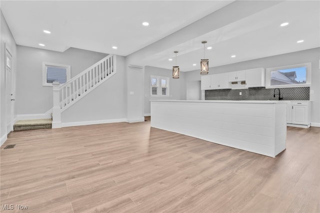 living area featuring stairs, recessed lighting, baseboards, and light wood-style floors