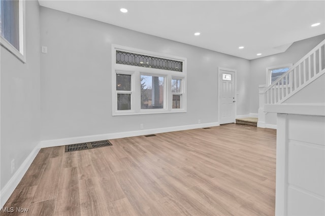 unfurnished living room featuring recessed lighting, visible vents, baseboards, stairs, and light wood-type flooring