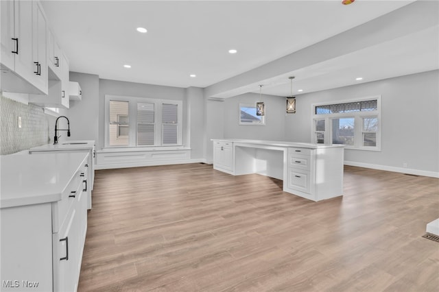 kitchen with a sink, light countertops, built in study area, and white cabinets