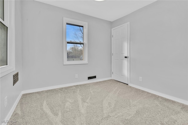 empty room featuring carpet floors, visible vents, and baseboards