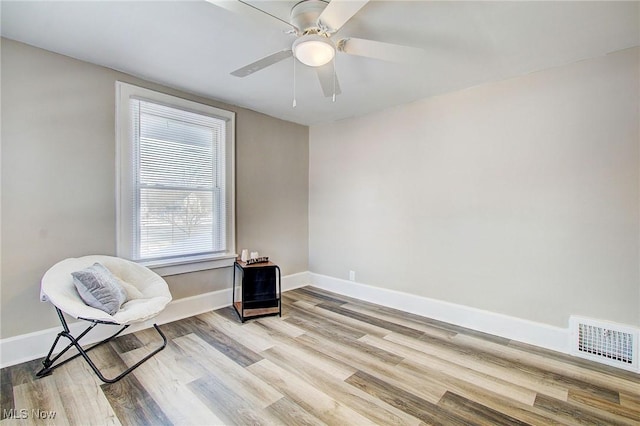 sitting room featuring baseboards, a ceiling fan, visible vents, and light wood-style floors