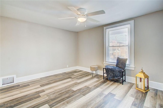 sitting room with light wood-style flooring, visible vents, ceiling fan, and baseboards