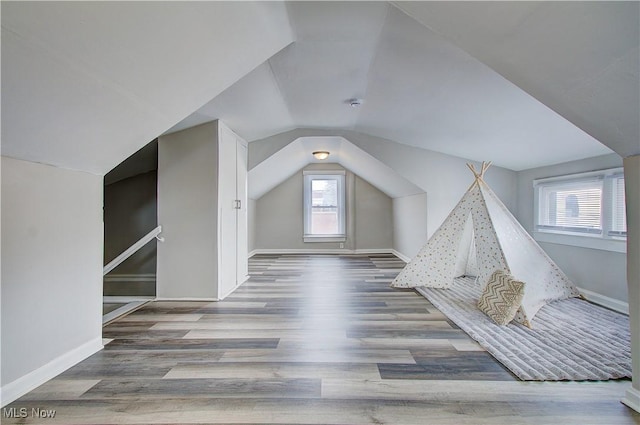 interior space with lofted ceiling, wood finished floors, and baseboards