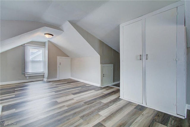 additional living space featuring light wood finished floors, baseboards, and vaulted ceiling