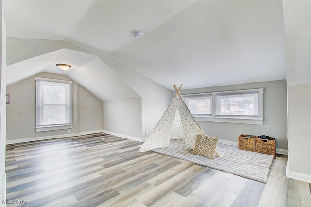 rec room with baseboards, vaulted ceiling, and light wood finished floors