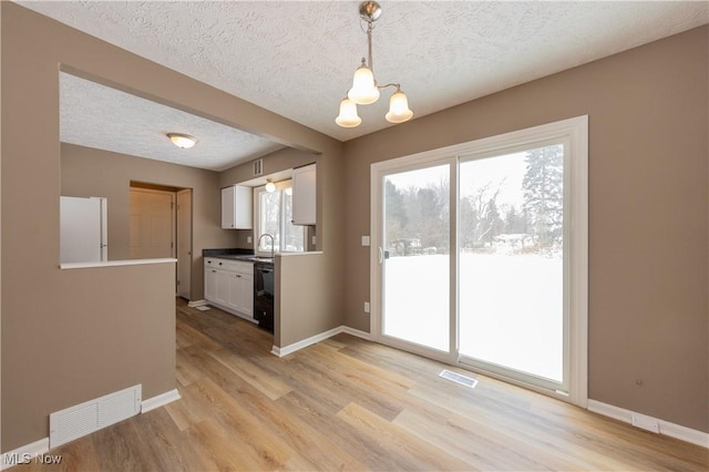 interior space featuring visible vents, white cabinets, decorative light fixtures, and freestanding refrigerator