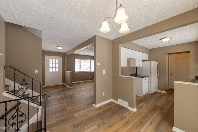 kitchen featuring hanging light fixtures, dark wood-style floors, white cabinetry, and freestanding refrigerator