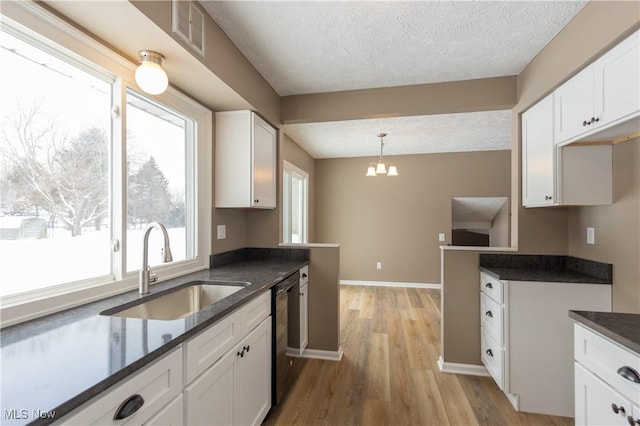 kitchen featuring hanging light fixtures, a sink, visible vents, and white cabinets