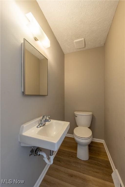 bathroom featuring a textured ceiling, wood finished floors, toilet, and baseboards