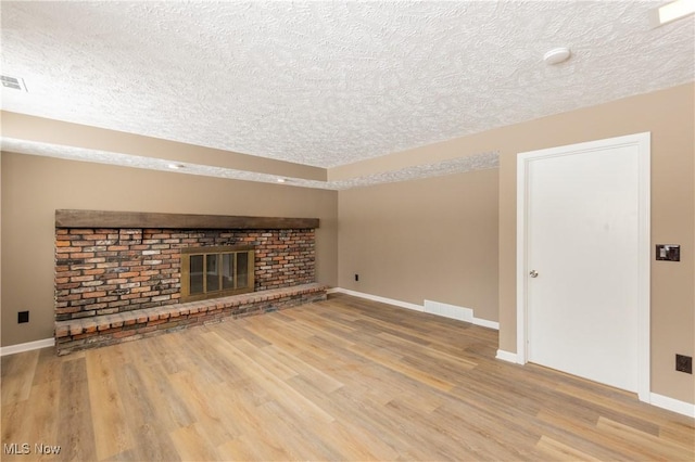 unfurnished living room with light wood finished floors, a fireplace, visible vents, and baseboards