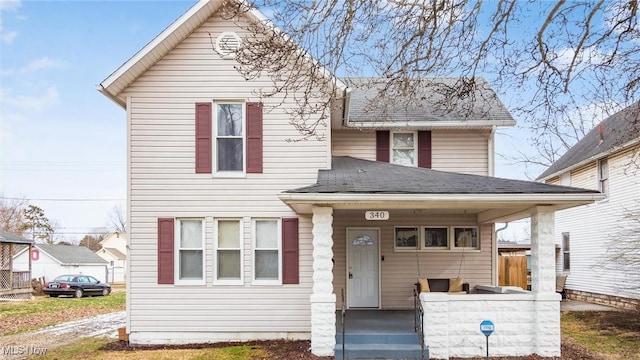 traditional-style home with a porch and roof with shingles