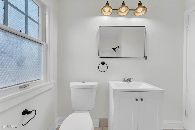 half bathroom with toilet, baseboards, and vanity