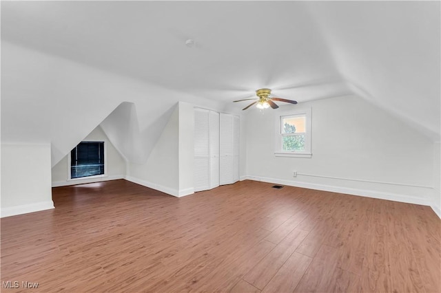 additional living space with visible vents, a ceiling fan, vaulted ceiling, wood finished floors, and baseboards