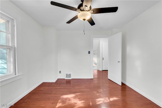 empty room featuring visible vents, dark wood finished floors, and baseboards